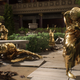 A collection of human beings turned to gold lament in a courtyard.